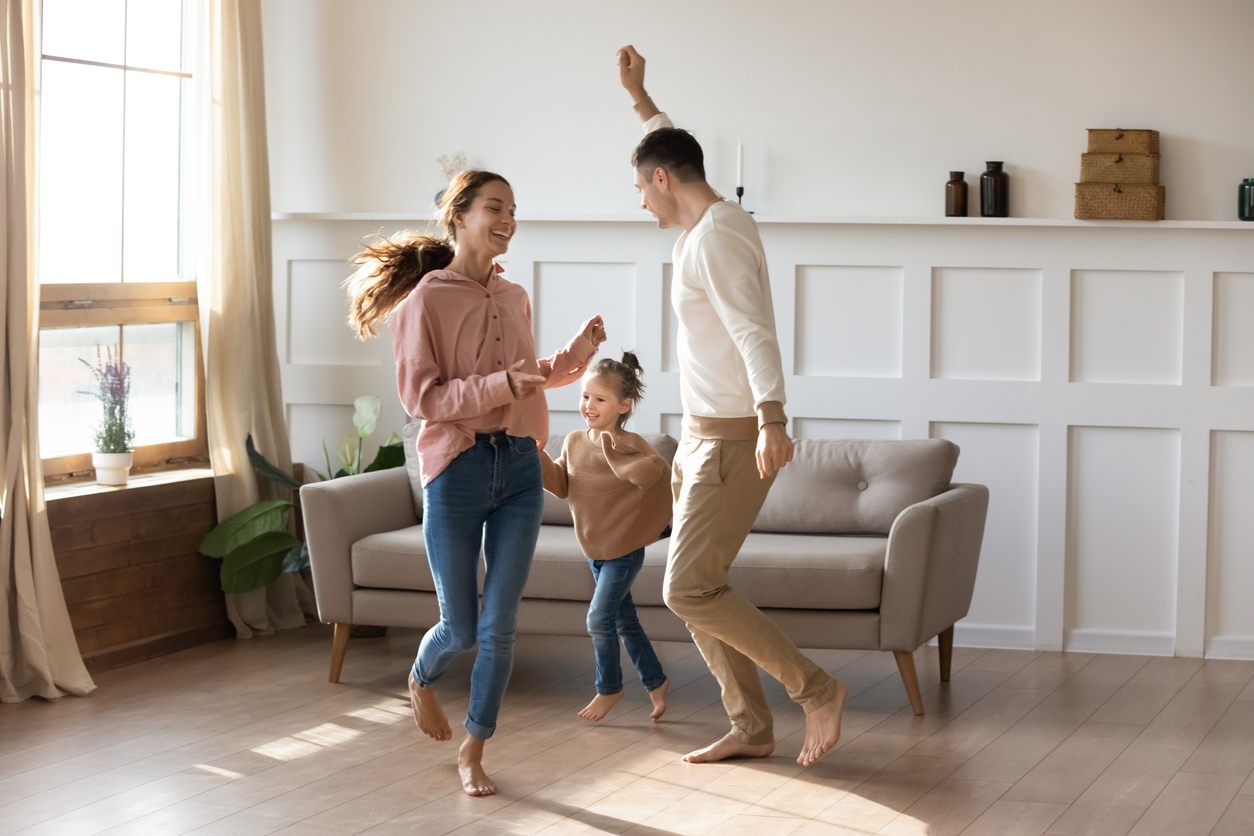 Familia feliz bailando en su nueva casa