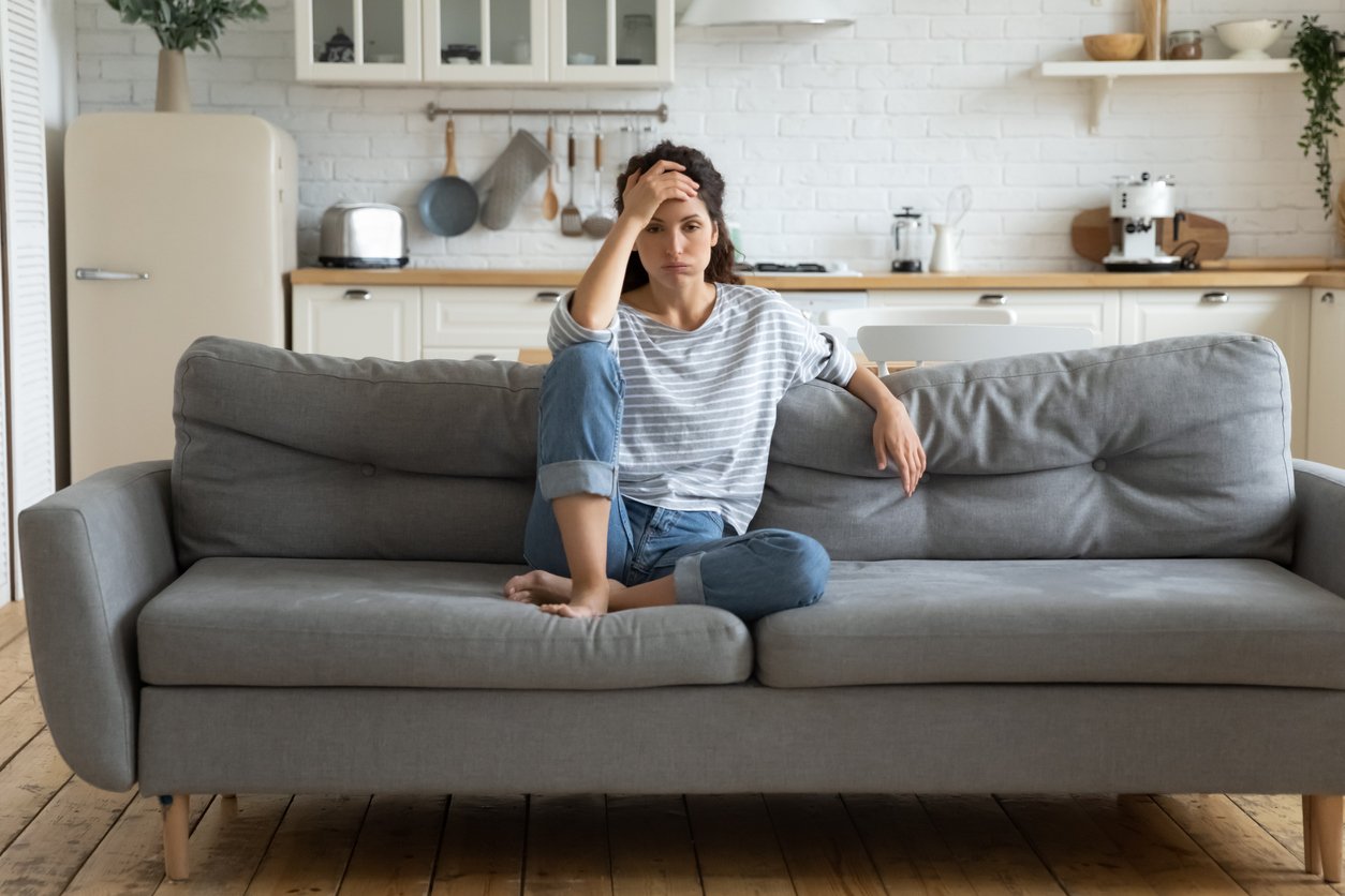 Mujer sentada en un sofá pensando en la compra de una casa 